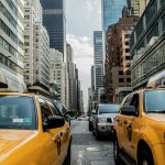 Image of a street with cars taxis and buildings