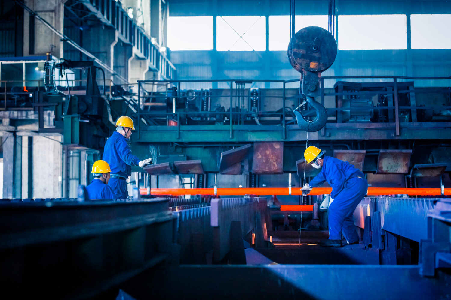 Photo of workers in hard hats and overalls working in a manufacturing warehouse. Used as a feature image for manufacturing software solution blog.